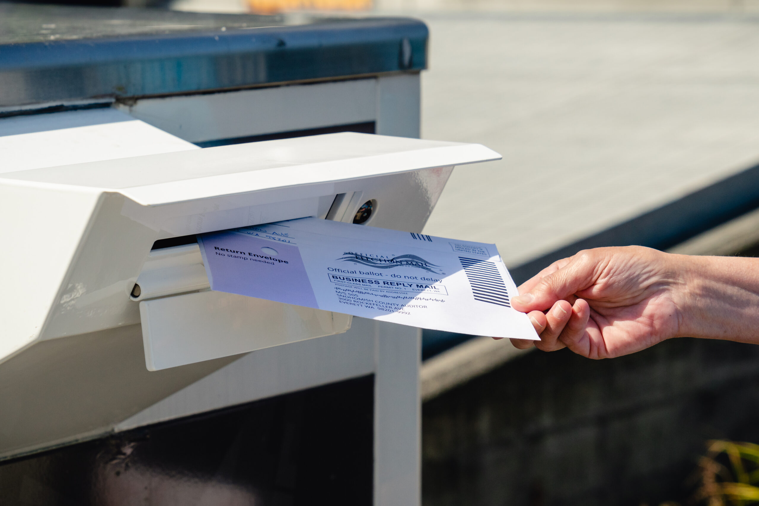A voter dropping a mail-in Ballot into a mail box.