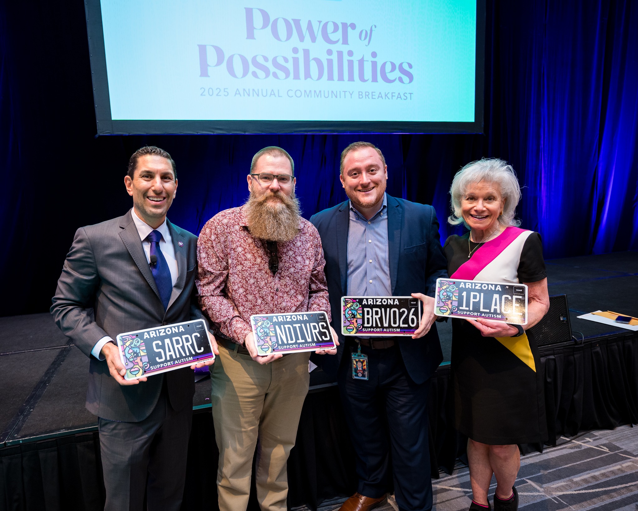 Southwest Autism Research and Resource Center's 27th Annual Community Breakfast presenting the new Arizona Support Autism license plate. From left to right : Daniel Openden, President and CEO of SARRC; Joe Bradley, Support Autism license plate artist; Arizona state senator Flavio Bravo (D) District 26; and Denis Resnik, founder, president and CEO of First Place AZ hold their own personalized license plates. The event was held in the Frank Lloyd Wright Ballroom at the Arizona Biltmore Resort on April 17, 2025. (Photo Courtesy of SARRC)
