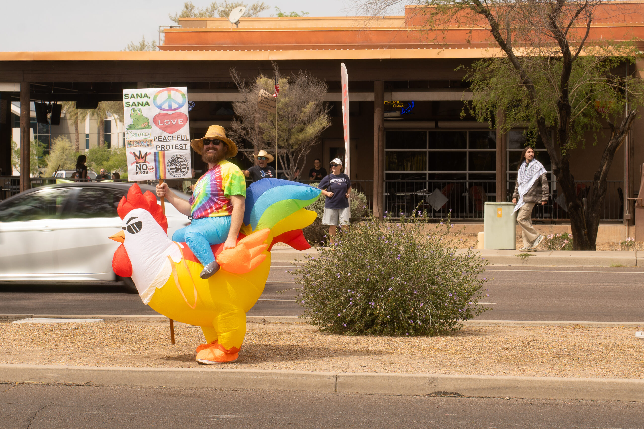 A man with an inflatable chicken suit protesting in the street median on Stapley Drive on March 28, 2026.